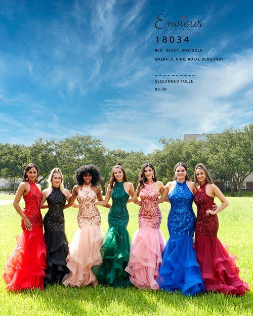 Seven beautiful ladies wearing long frocks, posing in an open area with grass and a clear sky