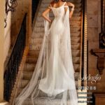 Beautiful bride in a long ivory white wedding gown, striking a pose on a staircase in a stunning villa